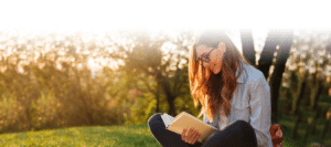 Person smiling while reading book outdoors