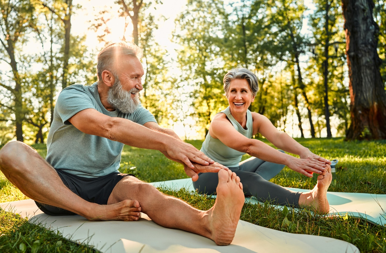 Senior couple doing yoga at park, pain-free