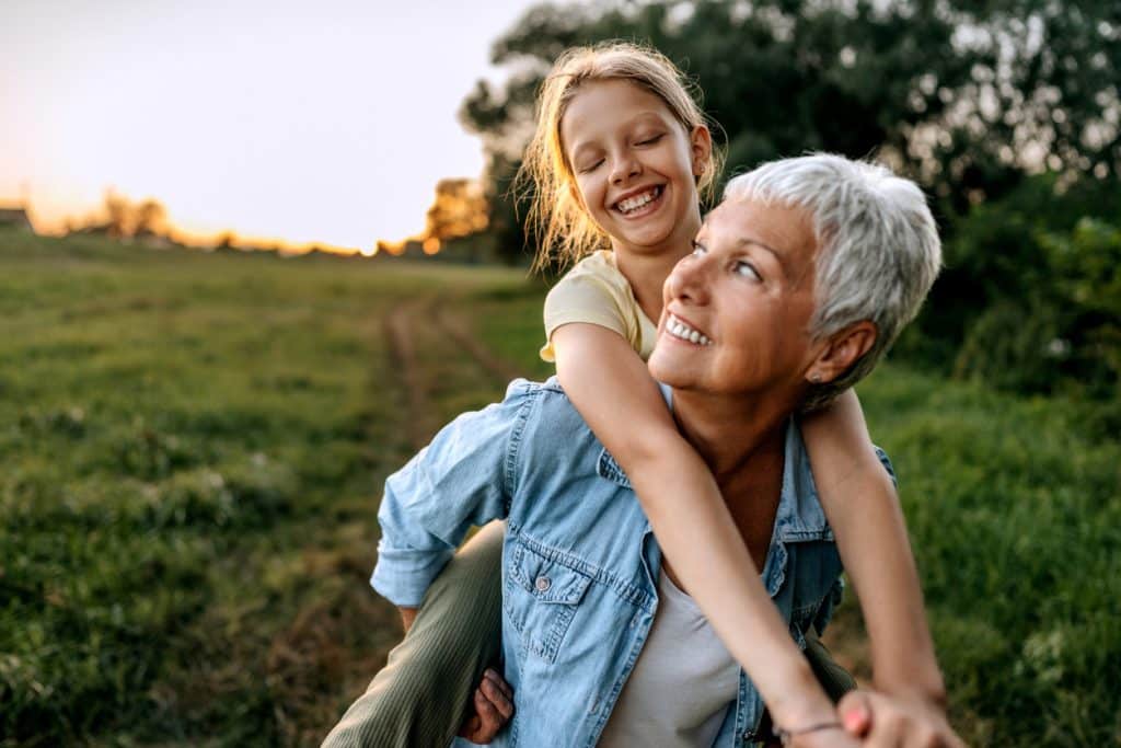 Woman carries granddaughter on back after recovery from spinal reconstruction surgery