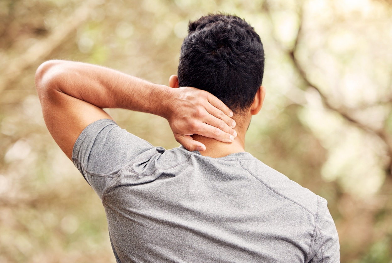 Back view of person holding back of neck in discomfort