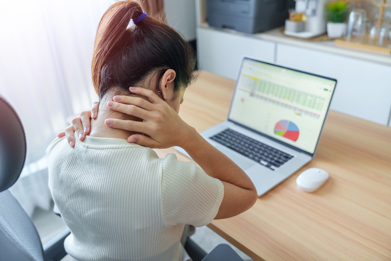 Woman sitting at desk holding back of neck