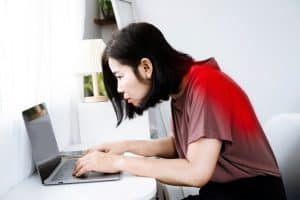 Woman hunched over computer at desk and working