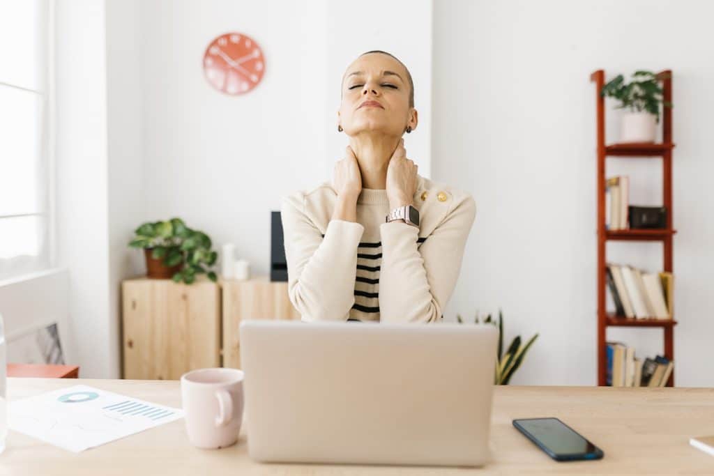 Adult suffering from neck pain in home office