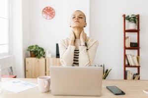 Adult suffering from neck pain in home office