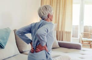 Older person massages aching lower back