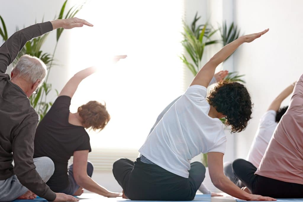Group of people in gym stretching backs