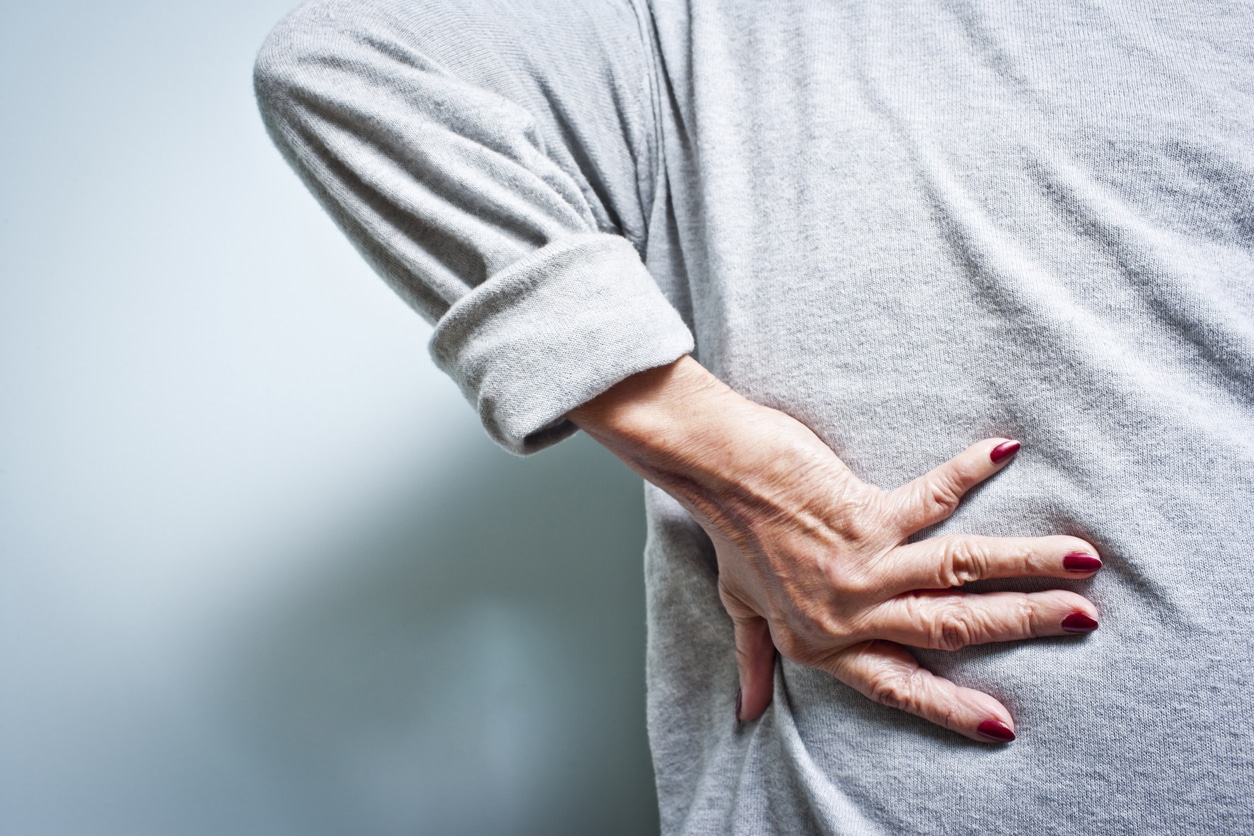 Person with back pain holding lower back