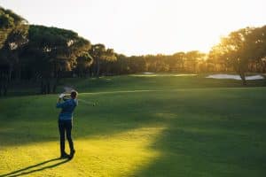 Golf player teeing off with beautiful sunset