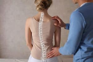 Physician evaluates scoliosis in patient