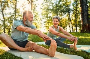Senior couple stretching on yoga mats outdoors