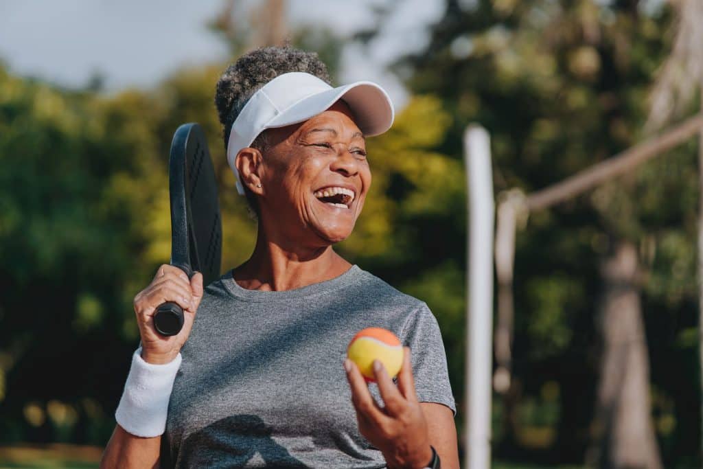 Mature person smiling while playing tennis on beach